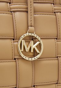Borsetta in pelle tessuta color tan con charm e dettagli in oro del logo MK, superficie liscia e design strutturato con cuciture in evidenza.