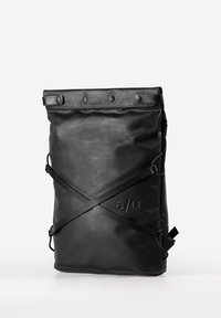 Schwarzer rechteckiger Roll-Top-Rucksack mit gekreuzten Riemen auf der Vorderseite und geprägtem "a/u"-Logo, steht aufrecht auf weißer Oberfläche.