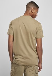 Kremfarget t-skjorte med korte ermer og rund hals, laget av myk bomull. Stoffet har en jevn tekstur, og designet er enkelt og tettsittende.