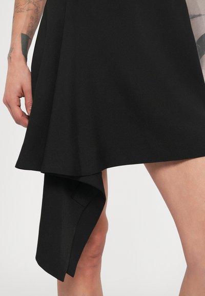 Čierne šaty s asymetrickým lemom, vyrobené z hladkej, textúrovanej látky. Obsahujú závesný detail vychádzajúci z lemu.