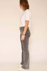 Jean flare gris taille haute, en mélange de coton, avec poches latérales et texture lisse. Associé à un T-shirt blanc à manches courtes et des baskets.