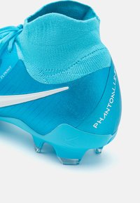 Sinine Nike Phantom Vision jalgpallikling, millel on valge swoosh, kootud pahkluu krae ja narmastega tald kindlate maapindade jaoks.