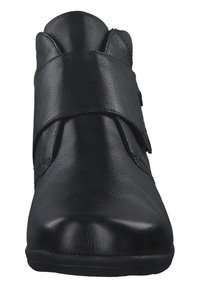Bottines en cuir noir avec une texture lisse, bout rond et large sangle sur le devant. Talon bas et détails de couture subtils.