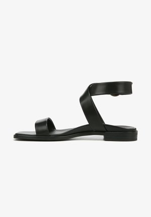 Black leather sandal with two narrow straps over the foot, a wide ankle strap, and a low, flat sole. Smooth texture, minimalistic design.