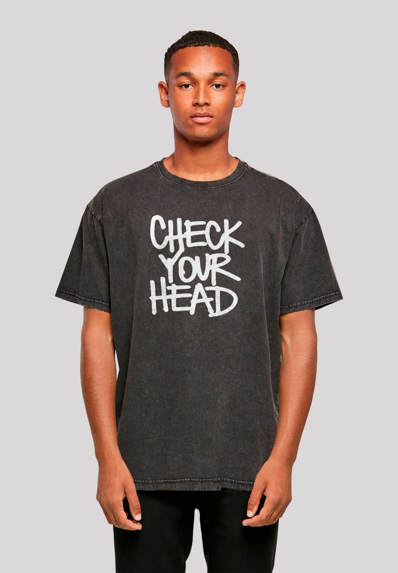 Black cotton t-shirt featuring a graphic print with the text "CHECK YOUR HEAD" in white, short sleeves, and a relaxed fit.