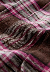 Woolen fabric in a brown and plaid pattern, featuring shades of pink and gray. Soft texture with visible weave detailing throughout.