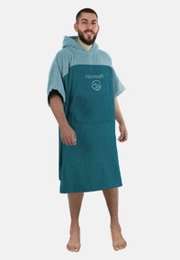 Kapuzentuch-Poncho in Türkis und Hellblau, aus Frottierstoff. Mit einer Vordertasche und besticktem Logo auf der Brust.