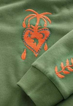 Zielona bluza z pomarańczowym haftem przedstawiającym serce z palmą, kroplami, gwiazdkami oraz wzorem liścia na mankiecie. Miękki materiał.