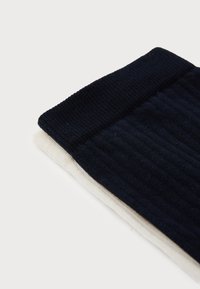 Due paia di calze a coste, una blu navy e una crema, con un motivo di lavorazione a maglia testurizzato e polsini elasticizzati a contrasto.