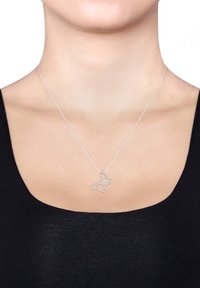 Collier en argent en forme de papillon avec une chaîne délicate, mettant en valeur des accents en cristal scintillants. Le design du papillon est ouvert et détaillé, reposant au-dessus d'un haut noir.