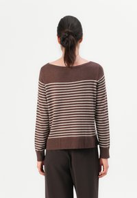 Maglione a righe marroni con scollatura ampia e maniche lunghe. Presenta righe orizzontali di un beige chiaro e un bordo a coste. Il tessuto appare morbido.