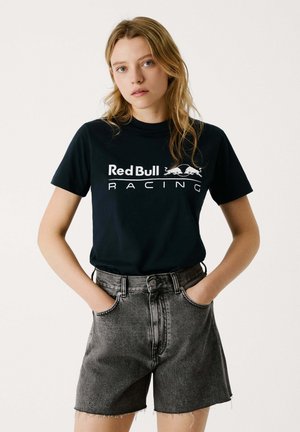 Tumed sinine T-särk valge "Red Bull Racing" logoga, sobitatud kõrge vöökohtadega mustade denim lühikesed püksid, millel on katkendlik serv.