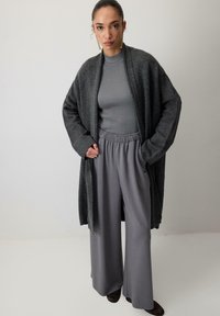 Pre veľké tmavošedé svetre, rebrovaný svetlosivý top a široké sivé nohavice. Hladké textúry, uvoľnený strih, jednoduchý dizajn.