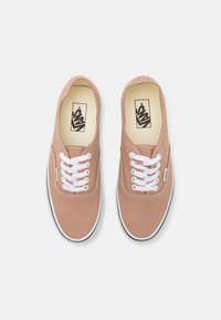 Paire de baskets Vans beiges avec lacets blancs et logo noir à l'intérieur, vues de dessus sur un fond blanc.