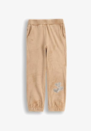 Beżowe, miękkie spodnie z polaru z elastycznym pasem, kieszeniami po bokach oraz wzorem srebrnych balonów w kształcie serca na lewej nodze.