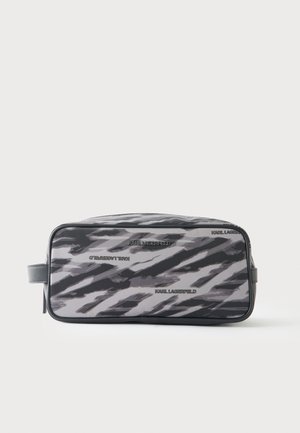 Trousse de toilette rectangulaire avec des rayures abstraites noires, grises et blanches et un motif de texte "Karl Lagerfeld", avec une poignée latérale.