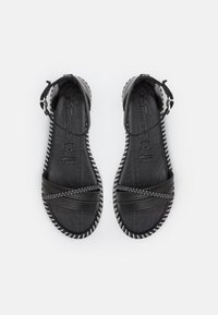 Black leather sandals with a flat sole, featuring cross straps, a buckle closure, and white stitching along the sole edge.