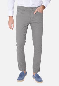 Chinos grigi con una vestibilità slim, realizzati in un tessuto misto cotone. Presentano tasche frontali e una tasca posteriore singola, abbinati a scarpe slip-on blu.