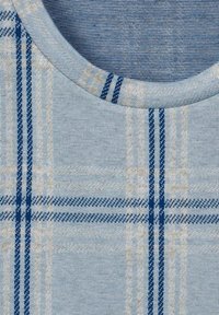 Ljust blått tyg med ett rutmönster i marinblått och beige. Rund halsringning och mjuk textur. Synliga vävda detaljer i ruterna.