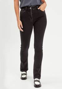 Jean noir taille haute avec une coupe slim, comprenant des poches avant et une fermeture à bouton. Design de jambe fuselée avec une texture lisse.