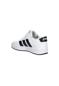 Baskets Adidas blanches avec rayures noires, sangle Velcro et talon rembourré, montrées sous un angle latéral-arrière sur un fond blanc.