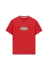 Czerwona bawełniana koszulka z okrągłym dekoltem i krótkimi rękawami. Na środku znajduje się naszywka z logo o prostokątnym kształcie z beżowymi akcentami, z napisem "GUESS JEANS".