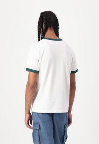 White t-shirt with green ribbed collar and sleeves, short sleeves, and a relaxed fit, shown from the back. Simple and classic design.