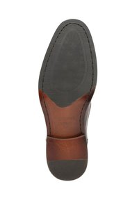 Suela de zapato de cuero marrón con un borde suave y redondeado, centro de goma negra texturizada y detalle cosido a lo largo del borde.
