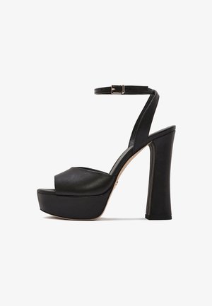 Zwarte leren platform sandaal met hoge hak, enkelbandje en zilveren gesp, dikke blokhak en open neus ontwerp.