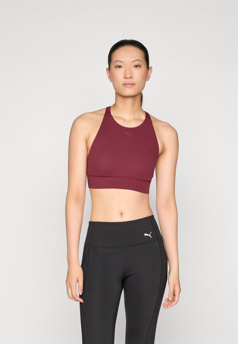 Bordeauxfärgad sport-bh med racerback-design, slät textur och logodetalj. Pairad med högmidjade svarta leggings med subtila detaljer.