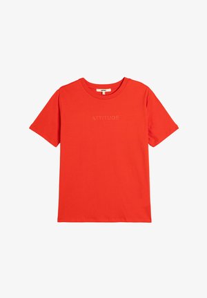 T-shirt en coton rouge à manches courtes, avec un col rond et le texte en relief 'ATTITUDE' sur la poitrine. Texture lisse.