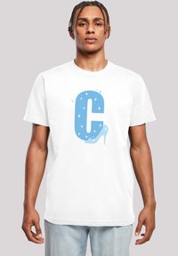 Hvit t-skjorte med korte ermer som har et stort blått grafikk av bokstaven "C" med glitrende detaljer og et design av høye hæler.