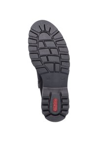 Black rubber boot sole with deep tread pattern, featuring a red logo and size indicator. Textured surface enhances grip and durability.