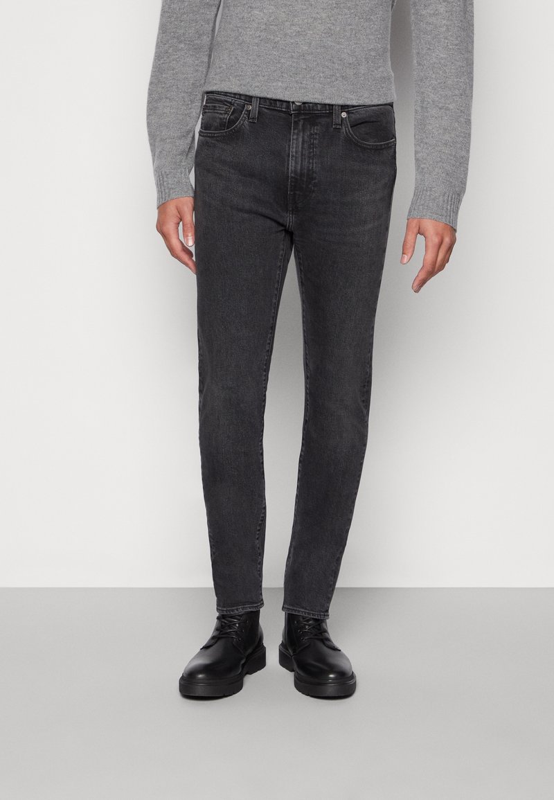 Jean noir coupe slim en denim avec une légère décoloration. Comprend cinq poches et des coutures contrastées. Associé à des bottes noires à lacets.