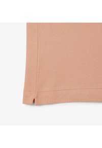 Tejido texturizado de color melocotón con un patrón sutil, que presenta aberturas laterales en el dobladillo para un detalle adicional y un acabado suave.