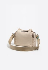 Beżowa torba z teksturowanej tkaniny z zamkiem błyskawicznym na górze, kieszenią boczną i regulowanym płóciennym paskiem. Posiada srebrne akcesoria i minimalistyczny design.