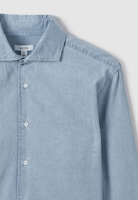 Cămașă din bumbac albastru deschis cu mâneci lungi, guler ascuțit și nasturi albi, mărimea medie, eticheta brandului vizibilă în interiorul gulerului.