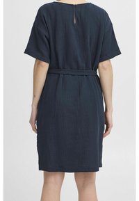Mörkblå klänning i strukturerad tyg, med korta ärmar, bälte i midjan och en nyckelhålsdetalj vid bakre halsringning.