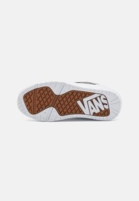 Semelle de sneaker blanche en caoutchouc avec un motif de grip texturé brun. Présente un logo Vans proéminent en blanc sur le côté. Design épuré et minimal.