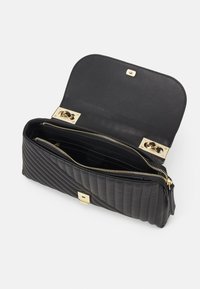 Svart vadderad läderhandväska med guldspänne. Interiören har flera fack och ett zippered fack för organiserad förvaring.