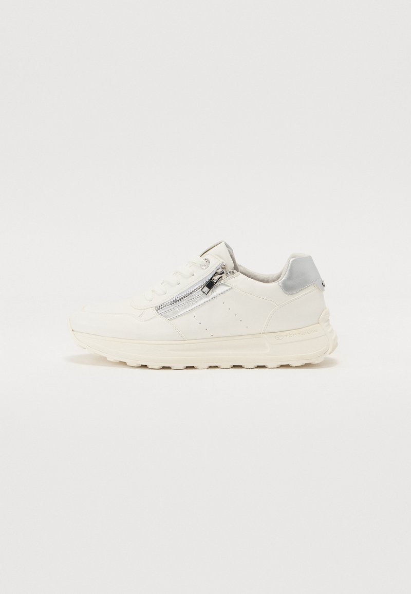 Fehér sneaker, strukturált felsőrésszel, ezüst színű cipzárral az oldalon és világosszürke sarkú sapkával. Vastag talpdesign.