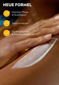Moisturizing cream applied to skin, showing a thick white texture. Light and dark skin tone contrast in the background. Clear, soft appearance.