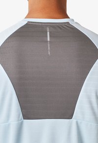 T-shirt de sport avec un panneau arrière texturé gris et des rayures horizontales, des manches bleu clair et un col rond.