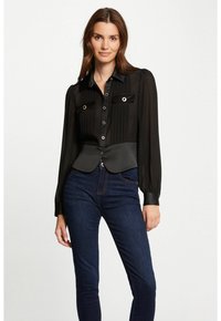 Blusa negra plisada con mangas largas, cierre de botones y bolsillos en el pecho abiertos; presenta una cintura entallada y una textura suave.