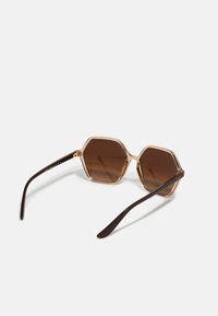 Hexagonal sunglasses with clear frames and brown tinted lenses, featuring dark brown arms and gold accents at the hinge.