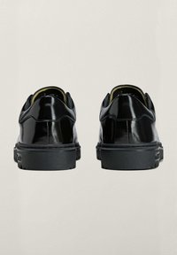 Crne cipele od lakirane kože s okruglim vrhom, niskim crnim gumiranim potplatom i kontrastnim šavovima na peti i rubu. Izdržljiv dizajn.