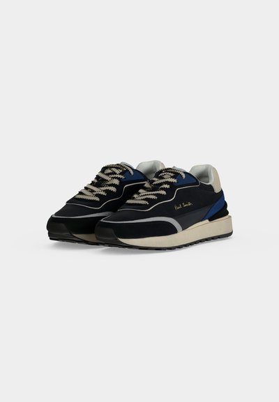 Ζεύγος μαύρων και μπλε sneakers χαμηλού προφίλ με μπεζ σόλες και λευκά κορδόνια με σχέδια, τοποθετημένα δίπλα-δίπλα σε λευκό φόντο.