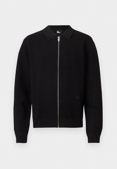 Μαύρο πλεκτό πουλόβερ με φερμουάρ, με ριμπ μανσέτες και τελείωμα, σταθερό γιακά και ασημένιο φερμουάρ στο κέντρο μπροστά.