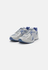 Gray and light blue athletic shoes with mesh upper, reinforced toe, textured sole, and lacing system. Features a logo on the side.