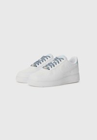 White leather sneakers with a low profile, featuring blue striped laces, perforated toe box, and textured rubber sole. Simple design with logo accents.